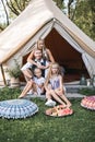 Happy family on a summer trip sitting near the big wigwam tipi tent on a sunny day. Family with children wearing stylish Royalty Free Stock Photo