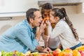 happy family beside table with fruits and vegetables applies little carrots to noses and looking at each other