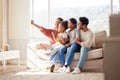 Happy family taking a selfie at home. Smiling parents with little children using a smartphone together sitting on the Royalty Free Stock Photo