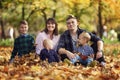 Happy family with three children are sitting in the autumn park among the fallen yellow foliage. Love and tenderness. Camping. Royalty Free Stock Photo