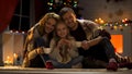 Happy family of three drinking hot cocoa near Christmas tree, miraculous day