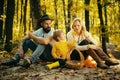 Happy family of three lying in the grass in autumn. A young family with small child having picnic in autumn nature at Royalty Free Stock Photo