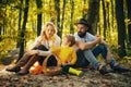 Happy family of three lying in the grass in autumn. A young family with small child having picnic in autumn nature at Royalty Free Stock Photo