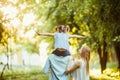 Happy family of three persons walking the grass in the park on sunset. happy daughter flying on father back Royalty Free Stock Photo