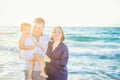 Happy family of three - pregnant mother, father and daughter embracing, laughhing and having fun walking on the beach. Family vaca Royalty Free Stock Photo