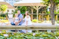 Happy family of three - pregnant wife, father and daughter having fun near pond with water lilies in the park. Family recreation, Royalty Free Stock Photo