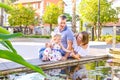 Happy family of three - pregnant wife, father and daughter having fun near pond with water lilies in the park. Family recreation, Royalty Free Stock Photo