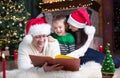 Happy family of three reading book together on Christmas evening Royalty Free Stock Photo