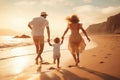 Happy family of three walking on the beach at sunset. Father, mother and little daughter having fun on summer vacation, rear view Royalty Free Stock Photo