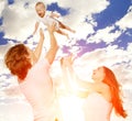 Happy family throws up baby boy against blue sky Royalty Free Stock Photo