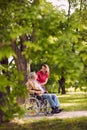 happy family time- elderly man in wheelchair talking with daughter in the park. Royalty Free Stock Photo