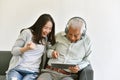 Happy family time, Smiling asian daughter and elderly father enjoy watching movie from laptop computer together. Royalty Free Stock Photo