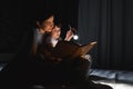 Happy family. Time for stories. Delighted happy cute mother and son enjoying a book before sleeping and using a flashlight Royalty Free Stock Photo