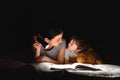 Happy family. Time for stories. Delighted happy cute mother and son enjoying a book before sleeping and using a flashlight Royalty Free Stock Photo