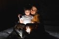 Happy family. Time for stories. Delighted happy cute mother and son enjoying a book before sleeping and using a flashlight Royalty Free Stock Photo
