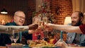 Happy family toasting sparkling wine at Christmas dinner table in living room