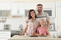 Happy family with tray of freshly oven baked buns at table in kitchen.