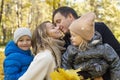 Happy family with two children in the autumn park hugging and kissing. Love, tenderness and warm relations in the family. Royalty Free Stock Photo