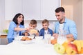 Happy family with two sons eating healthy morning breakfast with cornflakes and milk on cozy kitchen at dining table. Royalty Free Stock Photo