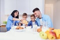 Happy family with two sons eating healthy morning breakfast with cornflakes and milk on cozy kitchen at dining table. Royalty Free Stock Photo