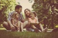 Happy family with two children in meadow reading book together. Royalty Free Stock Photo