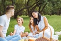 Happy family with two children relaxing on the lawn during a picnic in the green garden Royalty Free Stock Photo