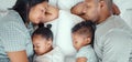 Happy family with two children sleeping together in their parents bed, from above. Loving parents cuddling two little Royalty Free Stock Photo