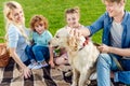 happy family with two children stroking dog while sitting on plaid Royalty Free Stock Photo