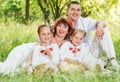 Happy family with two daughters sitting on green meadow