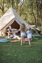 Happy family with two female children outdoors near the tent wigwam tipi in boho rustic style. Handsome man and pretty Royalty Free Stock Photo