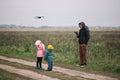 Happy family with two kids playing with drone in the field autumn time