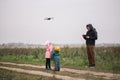 Happy family with two kids playing with drone in the field autumn time