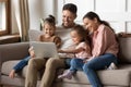 Happy family with two little daughters using laptop together