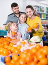 Happy family with two little girls looking for fresh oranges in supermarket Royalty Free Stock Photo