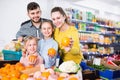 Happy family with two little girls looking for fresh oranges in supermarket Royalty Free Stock Photo