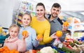 Happy family with two little girls looking for fresh oranges in supermarket Royalty Free Stock Photo