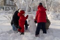 Happy family with two little girls in a winter park on a sunny day sculpts a snowman. Mom, dad and 2 daughters are Royalty Free Stock Photo