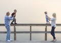 Happy family of two parents and children, one boys, baby girl, have good time on the river jetty. Sunset. Royalty Free Stock Photo