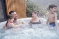 Happy family with two small children have fun in the jacuzzi. Cheerful young dad splashes water on his laughing cute son Royalty Free Stock Photo