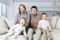 Happy family with two small children are sitting on the sofa in a bright living room. Warm relationship, love and tenderness Royalty Free Stock Photo