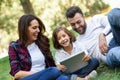 Happy family in a urban park playing with tablet computer Royalty Free Stock Photo