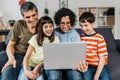 Happy family using a laptop computer while sitting on a sofa together at home. Royalty Free Stock Photo