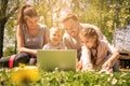 Happy family using laptop, sitting on the green grass. Family en Royalty Free Stock Photo