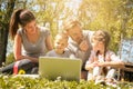 Happy family using laptop, sitting on the green grass. Family en Royalty Free Stock Photo