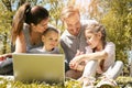 Happy family using laptop, sitting on the green grass. Family en Royalty Free Stock Photo