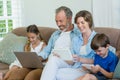 Happy family using mobile phone, digital tablet and laptop in living room Royalty Free Stock Photo