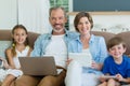 Happy family using mobile phone, digital tablet and laptop in living room Royalty Free Stock Photo