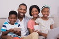 Happy family with various technologies sitting on sofa at home Royalty Free Stock Photo