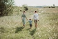 Happy family walking in field of blooming flowers from behind, dad mom and son, rear view Royalty Free Stock Photo