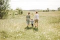 Happy family walking in field of blooming flowers from behind, dad mom and son, rear view photo Royalty Free Stock Photo